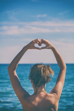 Kız plajda elleriyle kalp şekil verme