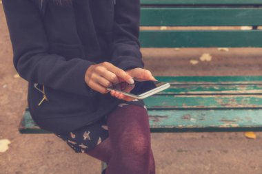 Açık havada akıllı telefon kullanan genç bir kadın.