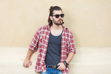 saç modeli güneş gözlüğü ve trendy kıyafetler bej duvar arka plan üzerinde poz ile yakışıklı adam 