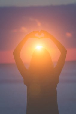 Kız plajda elleriyle kalp şekil verme