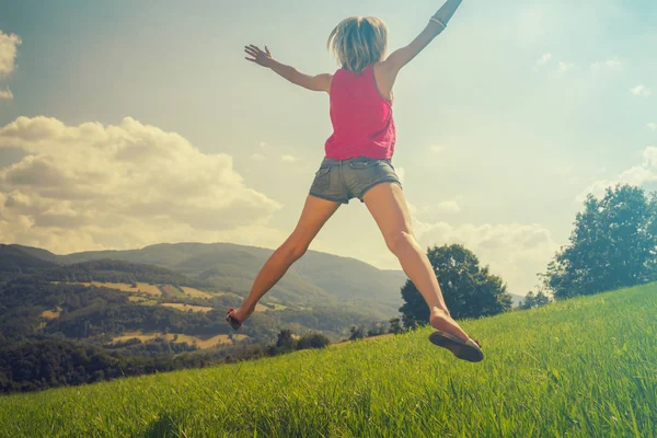 arkadan görünüşü kadın kaldırdı elleriyle yeşil çim güneşli gün atlama 