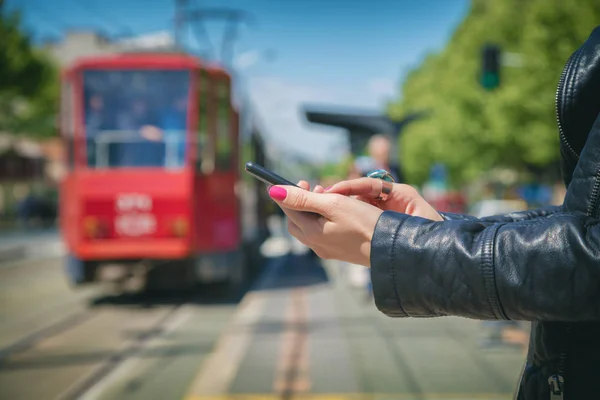 Γυναικεία Χέρια Πληκτρολόγηση Smartphone Ενώ Στέκεται Στο Σταθμό Θολή Τραμ — Φωτογραφία Αρχείου