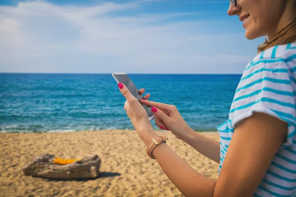 Kumsalda yürürken Smartphone kullanan kadın 