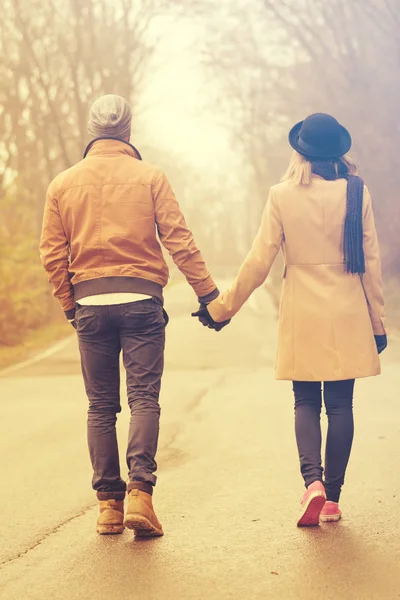 sweet couple holding hands and walking in autumn park