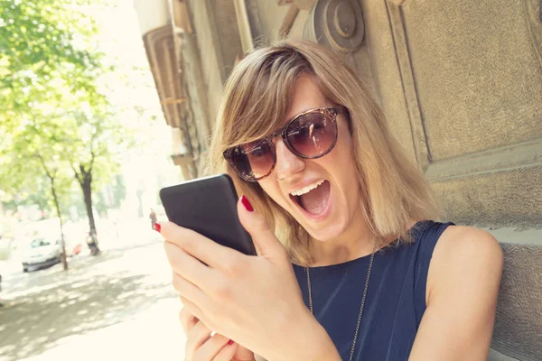 Έκπληκτος Γυναίκα Γυαλιά Ηλίου Χρησιμοποιώντας Smartphone Ενώ Ακουμπά Στον Τοίχο — Φωτογραφία Αρχείου