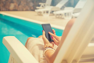 Açık havada akıllı telefon kullanan genç bir kadın.