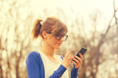 Kızıl saçlı kadın parkta duran Smartphone kullanarak