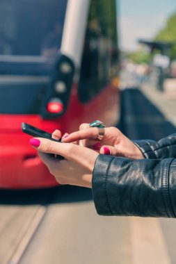 arka plan üzerinde bulanık tramvay ile smartphone istasyonda dururken yazarak eller  