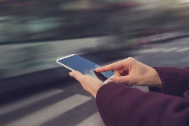 Açık havada akıllı telefon kullanan genç bir kadın.