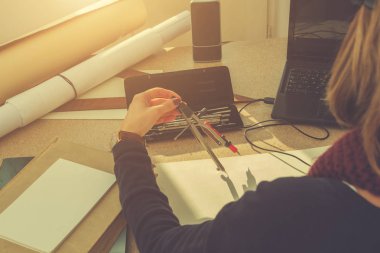 Kadın mimar parlak güneşli oda bir proje üzerinde çalışıyor. Optik odaklanma üzerinde lamba vardır