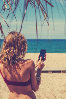 Açık havada akıllı telefon kullanan genç bir kadın.