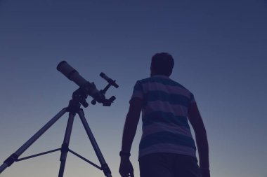 Genç adam geceleri bir teleskop kullanma