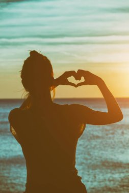 Kız plajda elleriyle kalp şekil verme