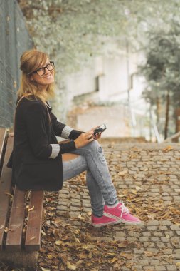 Açık havada akıllı telefon kullanan genç bir kadın.