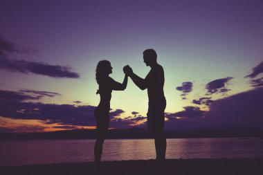 Çift sahilde günbatımı içinde zevk / gündoğumu kez