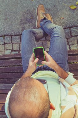 tahta bankta oturan ve smartphone açık, en iyi görünümü'nü kullanarak adam 