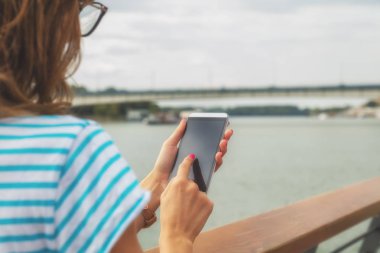 arkadan görünüşü seafront adlı dururken Smartphone cep telefonu ile mesaj yazarak kadın 