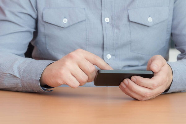 businessman wearing grey shirt typing on smartphone, close-up
