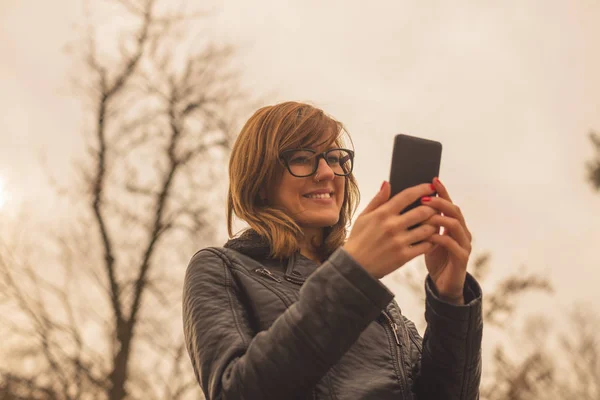 Visel Szemüveget Gépelés Smartphone Homályos Természetes Háttér Állva Kabát — Stock Fotó