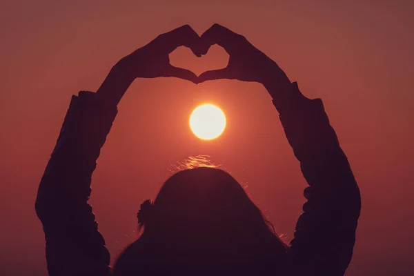 Arkadan Görünüşü Kadın Kalp Işareti Turuncu Ateşli Günbatımında Gösterilen Kaldırdı — Stok fotoğraf