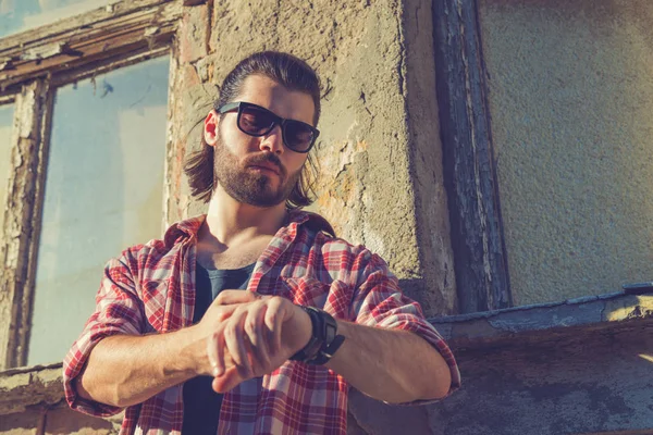 yandan eski evin yakınında dururken bakarak trendy kıyafetler giyen adam 