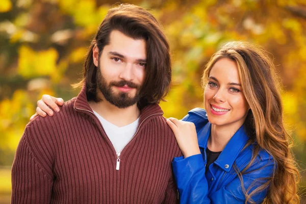 smiling gorgeous woman hugging happy handsome man with blurred autumn forest on background