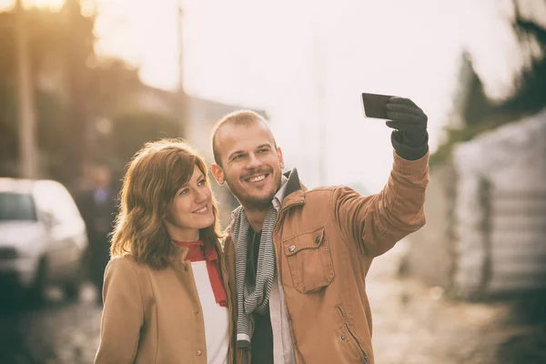 happy sweet couple taking selfie with smartphone outdoor