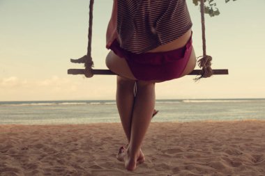 Okyanus ile kumlu bir plaj üzerinde sallanan kız / deniz manzaralı. Optik odaklanma ayakları üzerinde olduğunu.