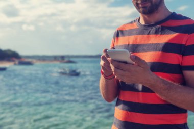 Genç adam cep telefonu kullanarak / smartphone Okyanusu yakın.