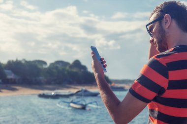 Genç adam cep telefonu kullanarak / smartphone Okyanusu yakın.