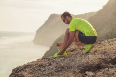 İpe çalışan / uçurumdan denize yakın tarihinde Spor Ayakkabı Koşu / okyanus.