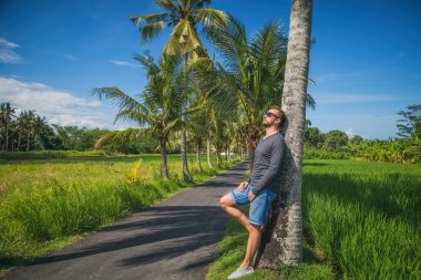 Palmiye ağaçları ile boş road yakınındaki ayakta adam.