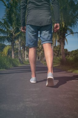 Bir adamın geri yürürken aracılığıyla palm - ağaçlar bir sokak detay.