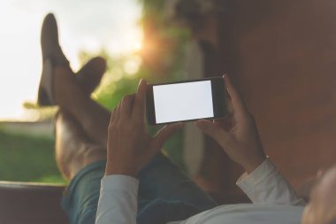 Kanepede yatan ve cep telefonu kullanan adam.