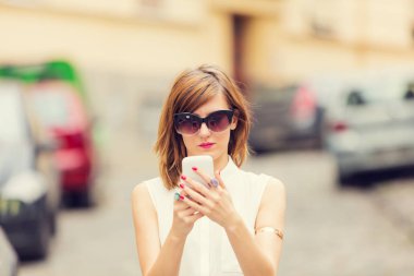 Açık havada akıllı telefon kullanan genç bir kadın.