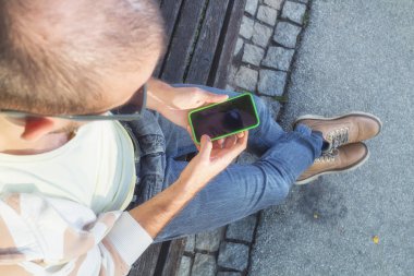 Genç adam dışarıda akıllı telefon kullanıyor.