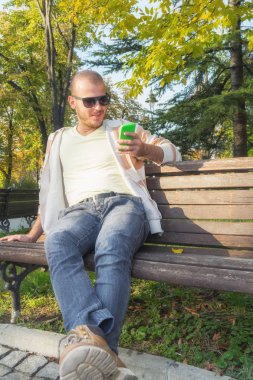 Genç adam dışarıda akıllı telefon kullanıyor.