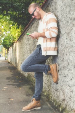 Genç adam dışarıda akıllı telefon kullanıyor.