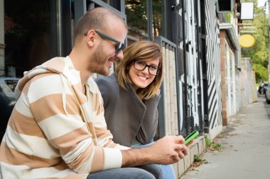 Cep telefonu açık havada kullanarak iki genç yetişkinler.