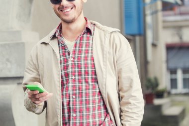 Modern Genç adam açık havada cep telefonu kullanarak.