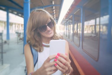 Bir tren istasyonunda cep telefonu kullanarak sevimli genç kız.