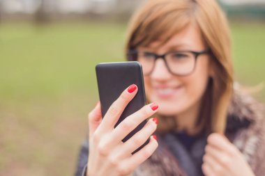 Parkta cep telefonu kullanan genç kız.