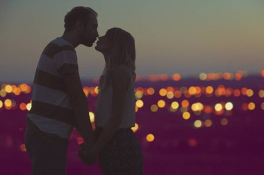 Genç bir çift arka planda şehir manzara öpüşme siluetleri.
