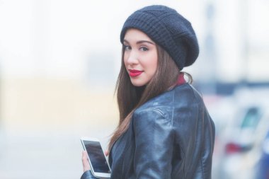 Açık havada akıllı telefon kullanan genç bir kadın.