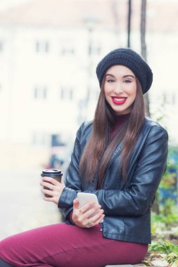 Açık havada akıllı telefon kullanan genç bir kadın.