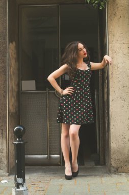 Sevimli kız bir bina giriş kapısı önünde poz.