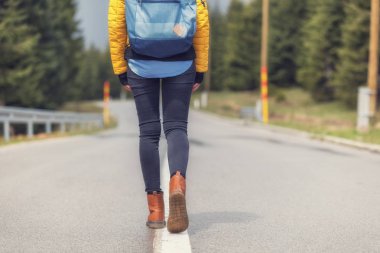 Boş banliyösü yolda yürüyen kız.