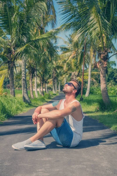 Man Zit Het Midden Van Een Lege Weg Met Palmbomen — Stockfoto