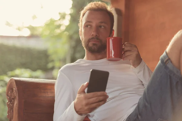 Hombre Sosteniendo Teléfono Celular Taza Café Sofá — Foto de Stock