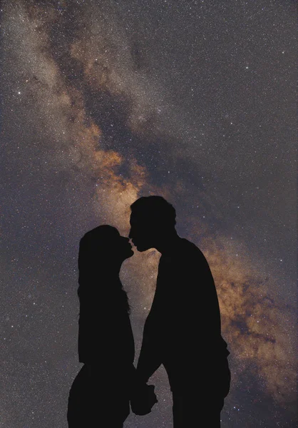 Silhouettes of a young couple under the starry sky.